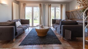 A living room with two sofas, a coffee table, and a staircase. - Spacious house with garden and river view (Port-sur-Saône)