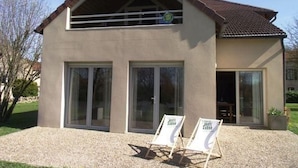 A two-story building with large windows and a sloped roof. There are two lounge chairs in front. - Spacious house with garden and river view (Port-sur-Saône)