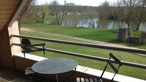 A balcony with a table and chairs, overlooking a grassy area and a body of water. - Spacious house with garden and river view (Port-sur-Saône)