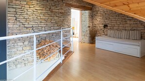 A room with a stone wall, wooden ceiling, and a white sofa. - Spacious house with garden and river view (Port-sur-Saône)
