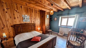 Una habitación de madera con una cama, una silla, una mesita y una ventana.