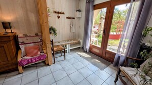 Una habitación con un banco de madera, una pequeña mesa, una silla, un armario de madera y una puerta que da al exterior.