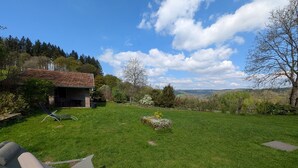 Un espacio al aire libre con césped, un edificio, una silla y vistas del paisaje.
