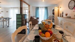 A dining area with a table set for two, featuring a fruit bowl, plates, and cups. - Cozy modern cottage with garden, 2 bedrooms (Venisey)