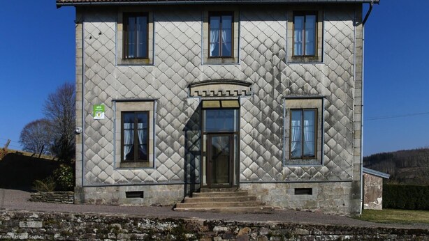 A two-story house with a symmetrical facade, a central entrance, and a tiled roof.
