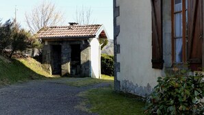 A rustic building with a gravel driveway leading to a stone structure with a tiled roof.
