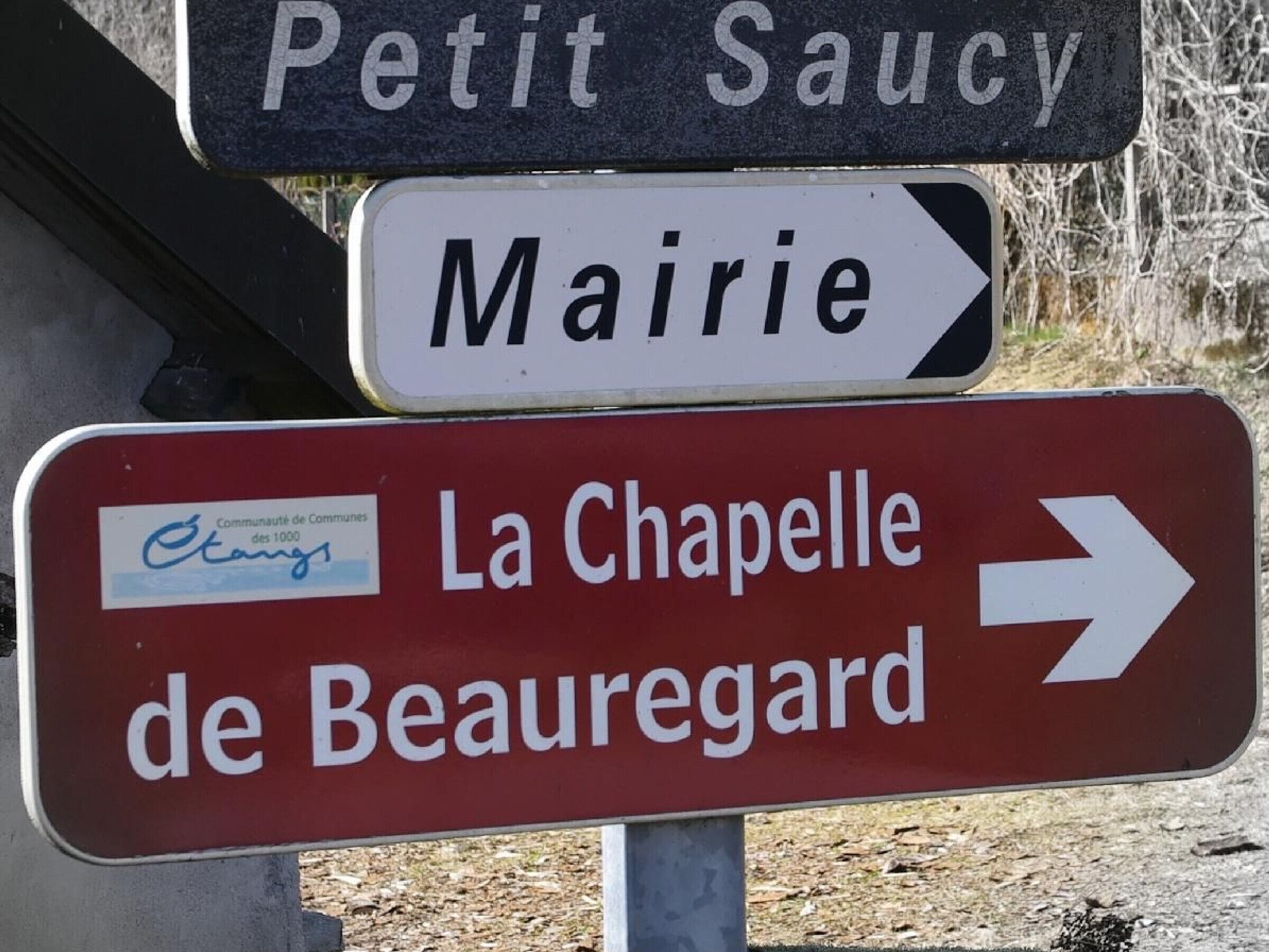 A directional sign with destinations: Petit Saucy, Mairie, and La Chapelle de Beauregard.