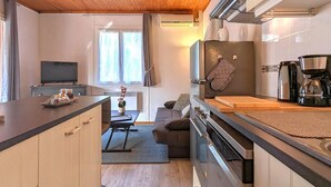 Une cuisine compacte avec un plafond en bois, un four encastré, une machine à café et un coin repas avec un canapé.