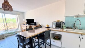 A modern kitchen with a dining table, chairs, a television, and a sink.
