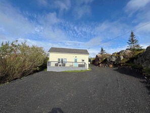 A single-story building with a flat roof, a fenced front yard, and a gravel driveway leading to the entrance.
