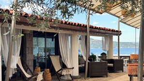 Un espace extérieur aménagé, abrité et doté de mobilier en osier, offrant une vue sur la mer.