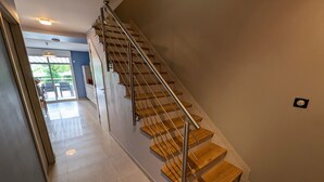A modern staircase with wooden steps and metal railings, leading to a room with a large window and a door.