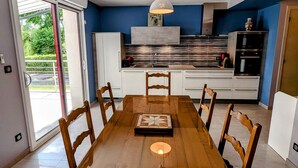 A modern kitchen with a dining table, chairs, and a pendant light.