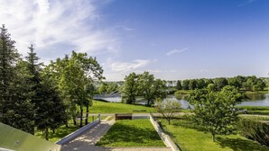 A view of a park with a gravel path, a bridge, and a lake.