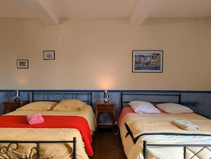 Una habitación con dos camas, cada una con cabecero, mesitas de noche y lámparas. En las paredes hay cuadros enmarcados.