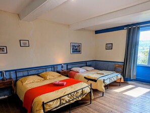 Une chambre avec deux lits, un plancher en bois et une fenĂȘtre avec des rideaux.