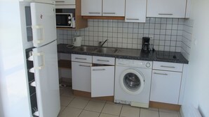 A compact kitchen with white cabinets, a built-in microwave, a coffee maker, and a washing machine. - Comfortable Pavilion in the Ognon Valley (Larians-et-Munans)