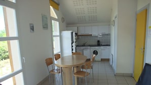 A compact kitchen with white cabinets, a sink, and a washing machine. There is a dining area with a round table and chairs. - Comfortable Pavilion in the Ognon Valley (Larians-et-Munans)