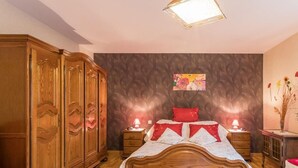 Un dormitorio con una cama de madera, dos mesitas de noche, un armario y un adorno floral en la pared.