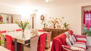 Un área de comedor con una mesa, sillas, un sofá y un reloj de pared.