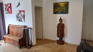 A living room with a wooden bench, a statue, and a painting on the wall.