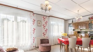 A modern living room with a sofa, a dining table with chairs, and a kitchen area with cabinets and a countertop. - Charming quiet pavilion, ideal for families or friends near the Vosges (Champagney)