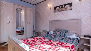 A bedroom with a bed, a wardrobe, a nightstand, and a wall-mounted light fixture. - Charming quiet pavilion, ideal for families or friends near the Vosges (Champagney)