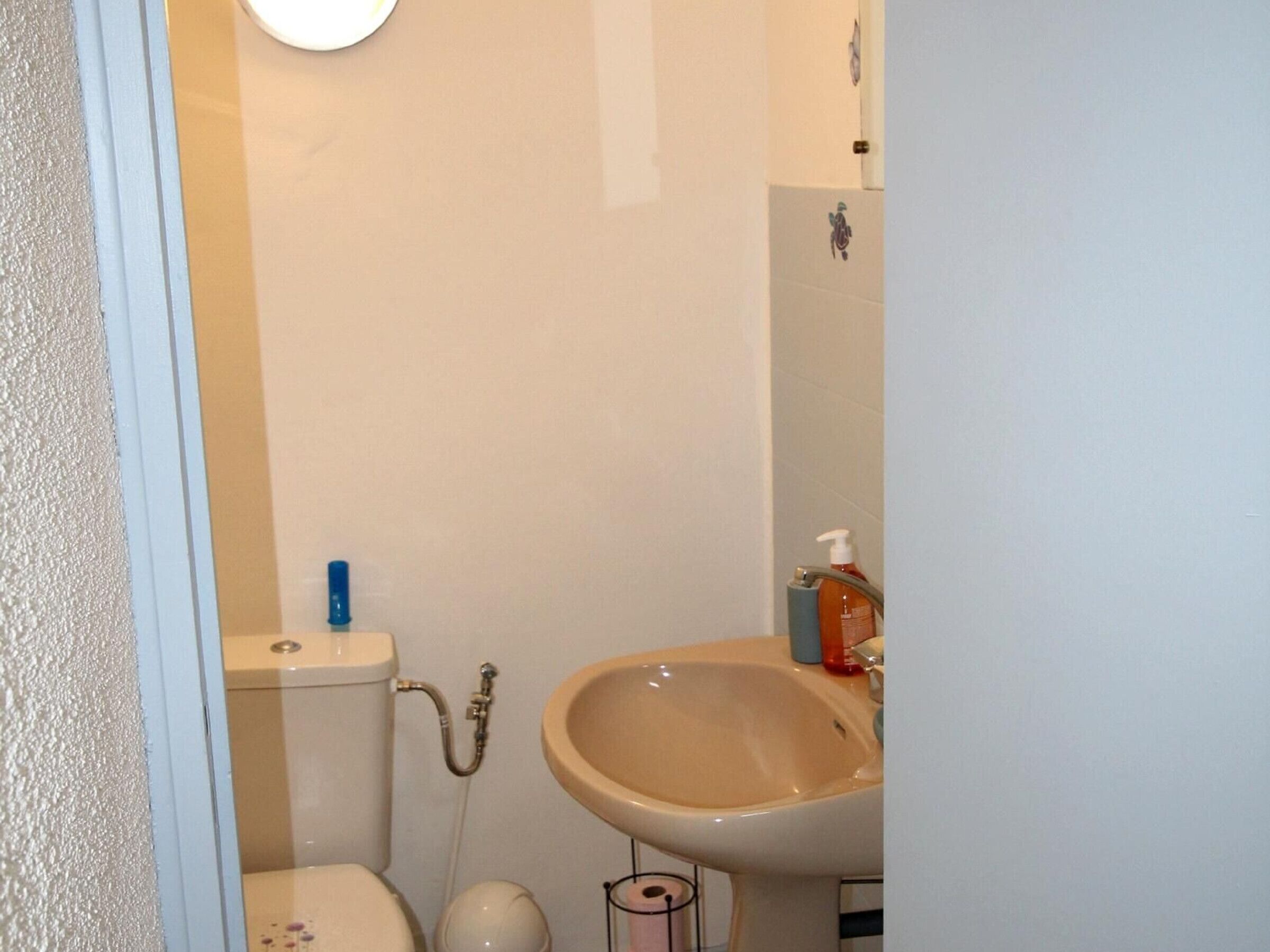 Een badkamer met toilet, hygiëneschuimer en wastafel.