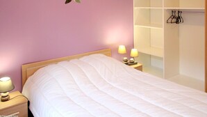 Een slaapkamer met een bed, bedlampen, een wandplank en een kledingrek.