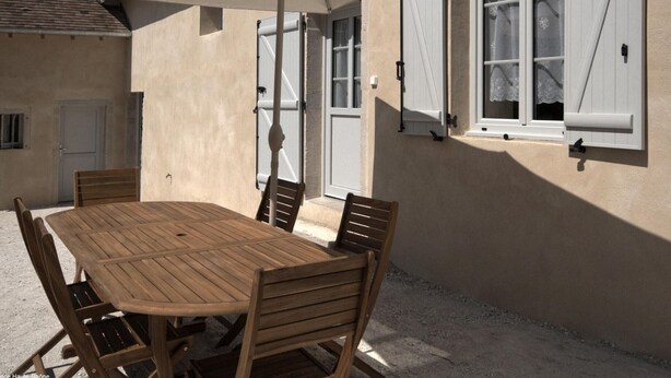 A wooden table with chairs and a large umbrella in an outdoor patio area.