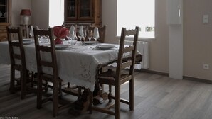A dining room with a table set for six, wooden chairs, a cabinet, and a window providing natural light.