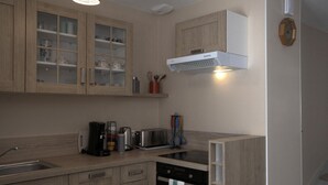 A modern kitchen with wooden cabinets, a built-in oven, a coffee maker, and a toaster.