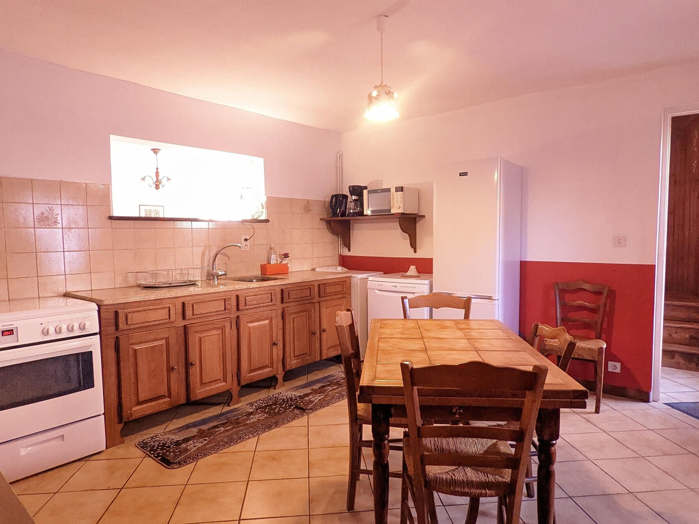 A compact kitchen with wooden cabinets, a stove, a microwave, and a dining table with chairs.