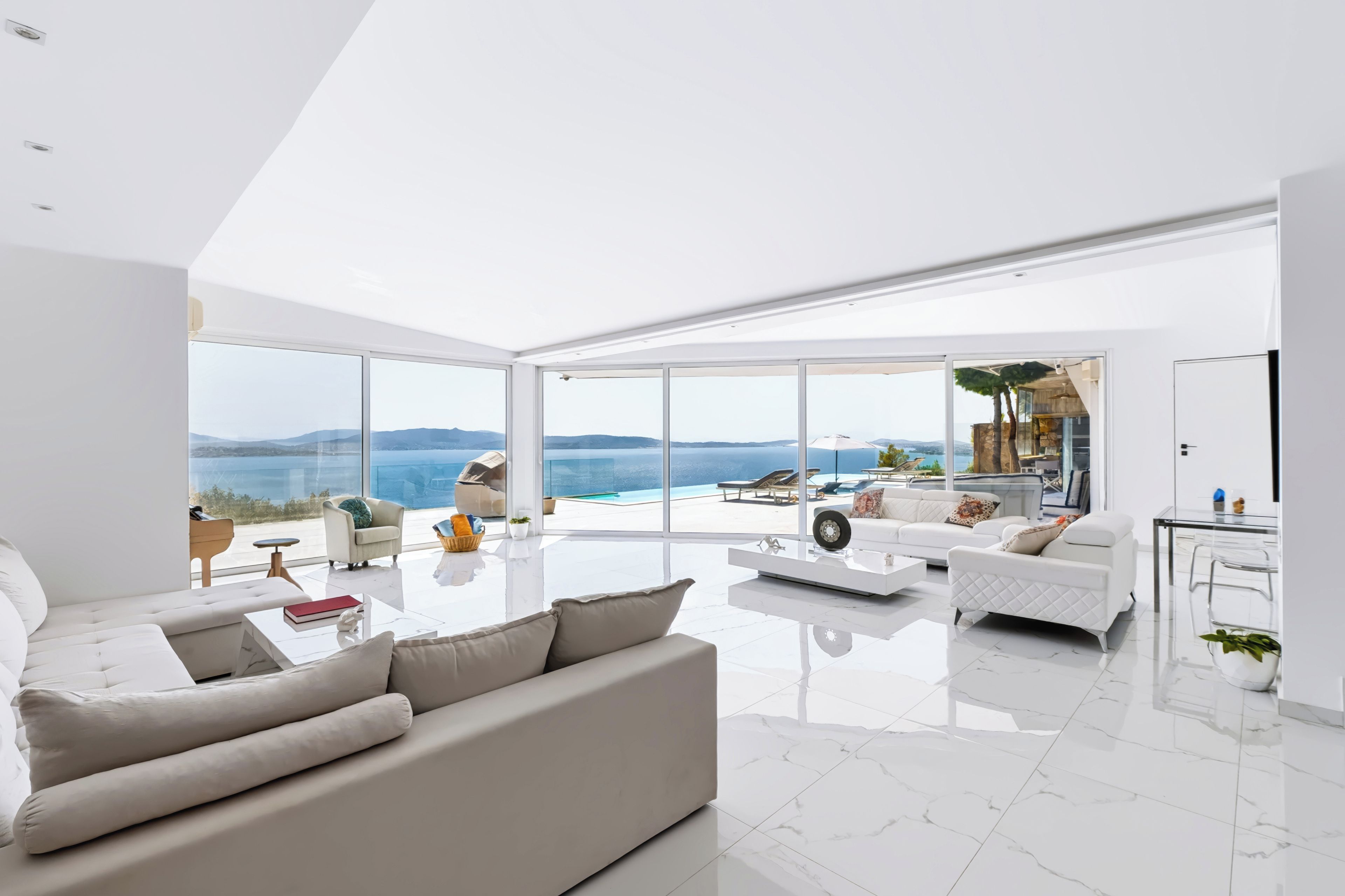 A modern living room with a large window, a sofa, a coffee table, and a view of the ocean.