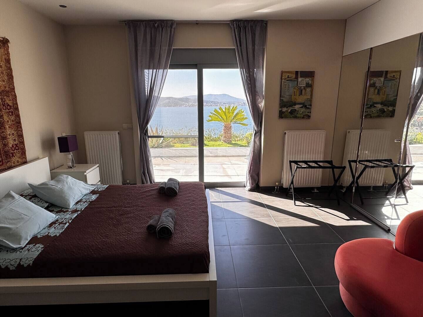 Ein Schlafzimmer mit Bett, Sessel, Heizkörper und Meerblick.