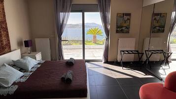 Ein Schlafzimmer mit Bett, Sessel, Heizkörper und Meerblick.