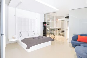 A modern bedroom with a bed, a wardrobe, and a seating area. - Villa Infinity (Megara)