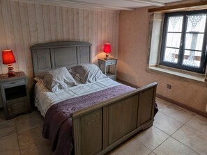 A bedroom with a wooden headboard bed, two bedside tables, a window with decorative glass, and a red lamp on each table.