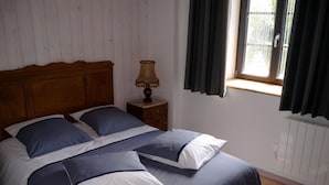 Un dormitorio con cabecera de madera, una mesita de noche con lámpara y una ventana con cortinas.