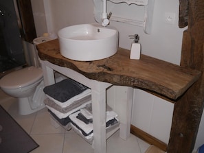 Un baño con lavamanos blanco, inodoro y tocador de madera.