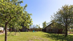 A grassy yard with a swing set, a stone building, and a tree. - Charming stone house in the heart of the Vosges (Saint-Bresson)