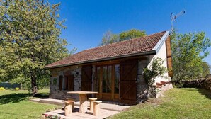 A rustic stone building with a tiled roof, wooden shutters, and a patio with benches. - Charming stone house in the heart of the Vosges (Saint-Bresson)