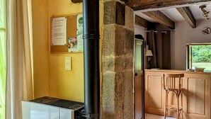 A kitchen with a built-in stove, wooden cabinets, and a window overlooking greenery. - Charming stone house in the heart of the Vosges (Saint-Bresson)