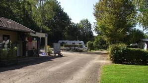Une route de campagne, avec un bâtiment sur la gauche et une remorque sur la droite.