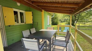 Une terrasse couverte avec une table et des chaises, des murs verdoyants et un plafond en bois.