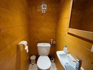 Ein kleines Badezimmer mit Holzvertäfelung, Toilette, Bidet und Waschbecken.