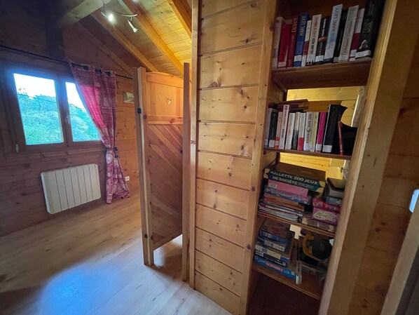 Ein Holzinnenraum mit Bücherregal, Heizkörper und einem fenster mit Vorhängen.