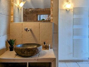 A bathroom with a stone sink, a mirror, and a towel rack.