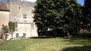 Un bâtiment historique en pierre, avec un grand arbre devant.