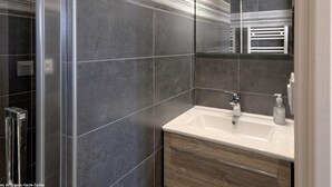 Un baño moderno con un espejo grande, un lavabo blanco y una zona de ducha.